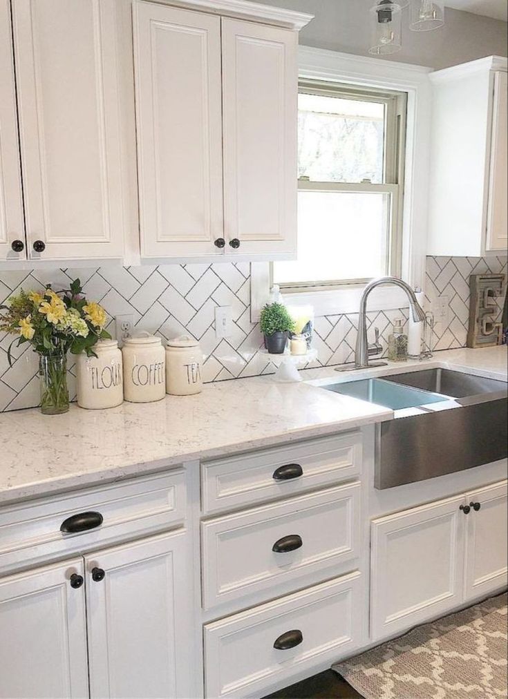 a kitchen with white cabinets, marble counter tops and stainless steel sink in the center