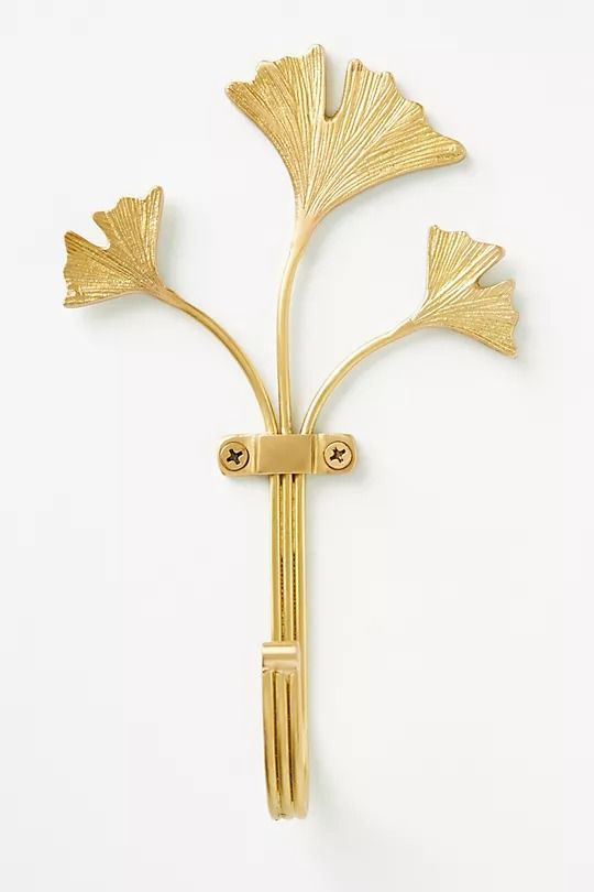 a gold brooch with three leaves attached to the back of it, on a white background