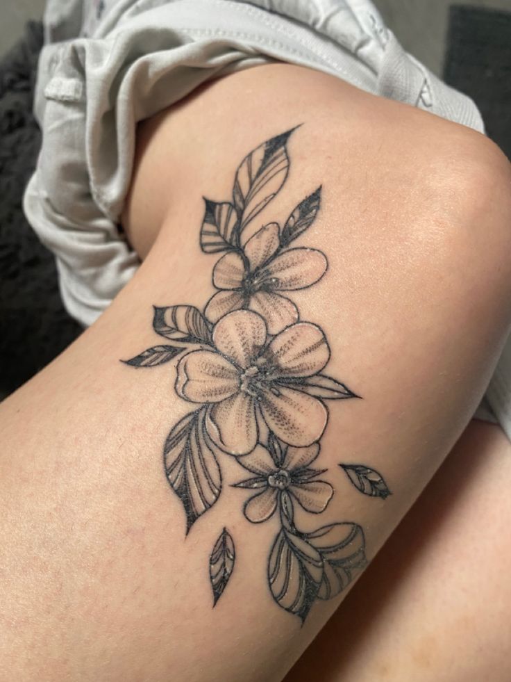 a woman's thigh with flowers and leaves tattoo on her leg, sitting down