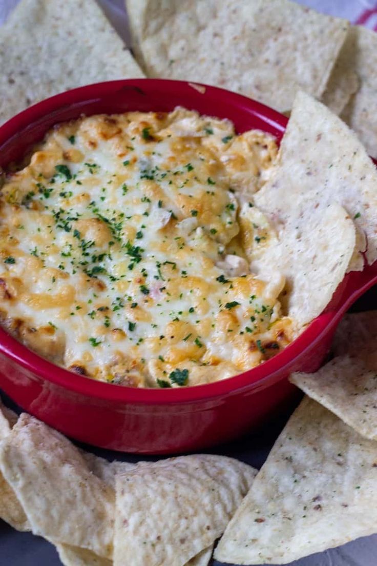 a red bowl filled with dip surrounded by tortilla chips