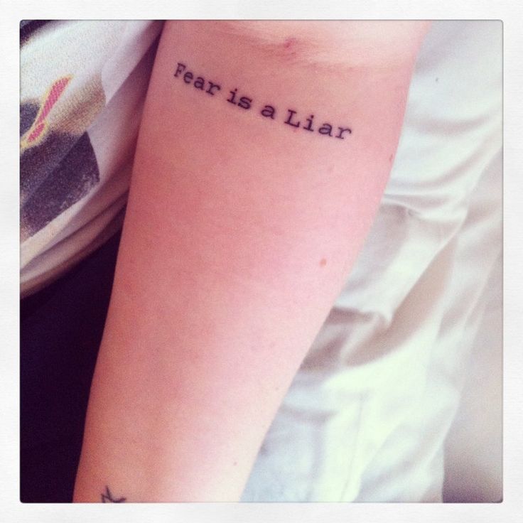 a woman's arm with the words fear is a liar on it