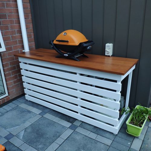 a grill sitting on top of a wooden counter next to a potted green plant