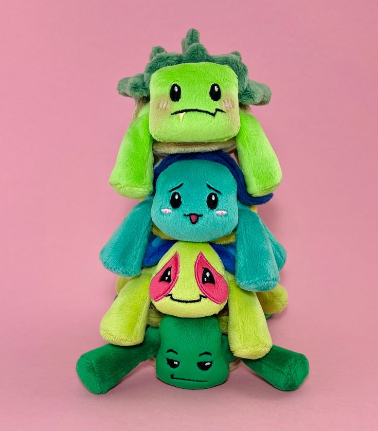 three stuffed animals stacked on top of each other in front of a pink background,