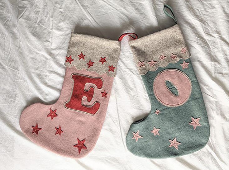 two christmas stockings laying on top of a bed next to each other, one with the letter e