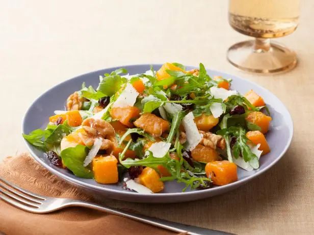 a blue plate topped with salad next to a glass of wine