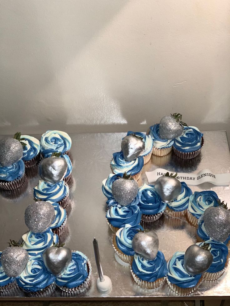 two cupcakes with blue frosting and silver decorations