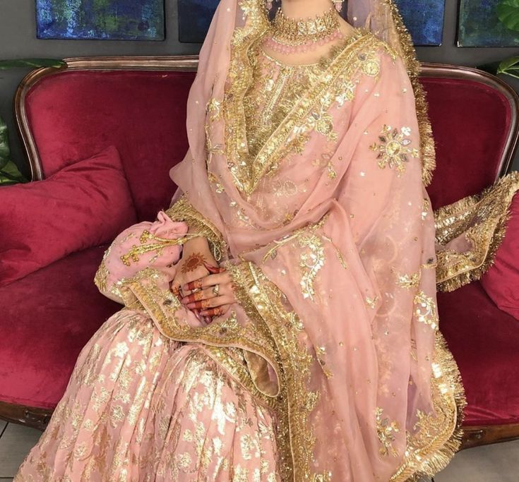 a woman in a pink bridal gown sitting on a red couch