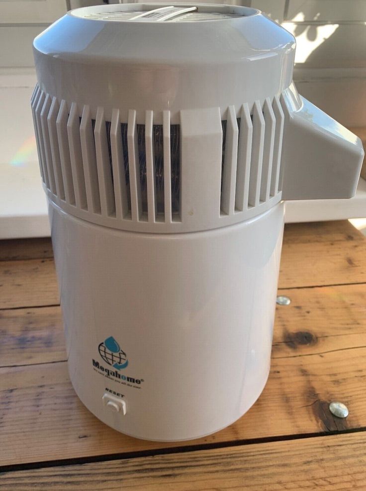 an air purifier sitting on top of a wooden floor next to a window