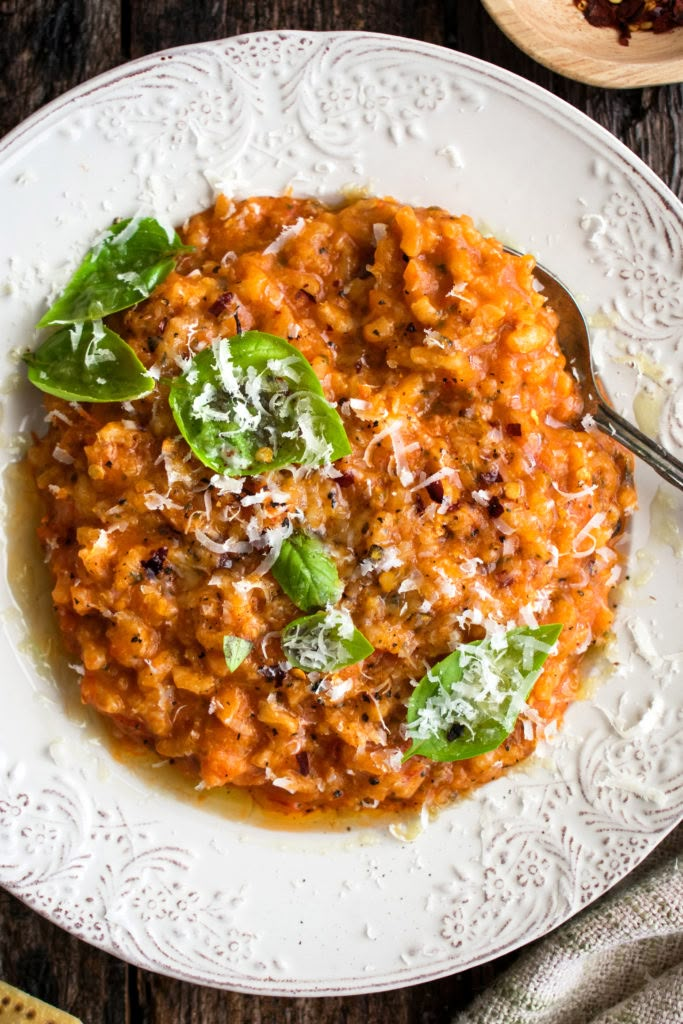 a white plate topped with pasta covered in parmesan cheese and spinach leaves