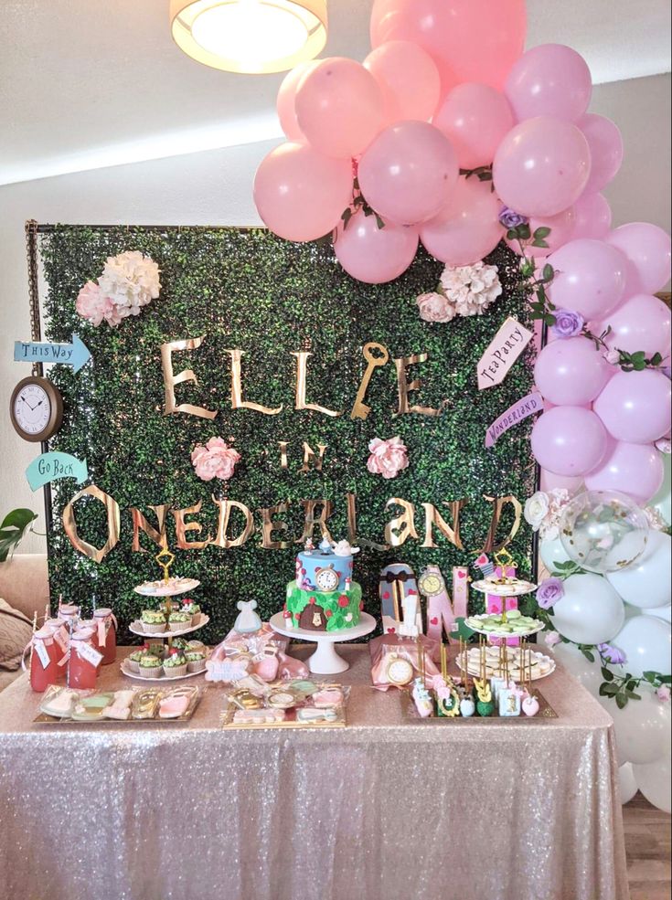 a table topped with lots of balloons and desserts on top of wooden tables covered in flowers