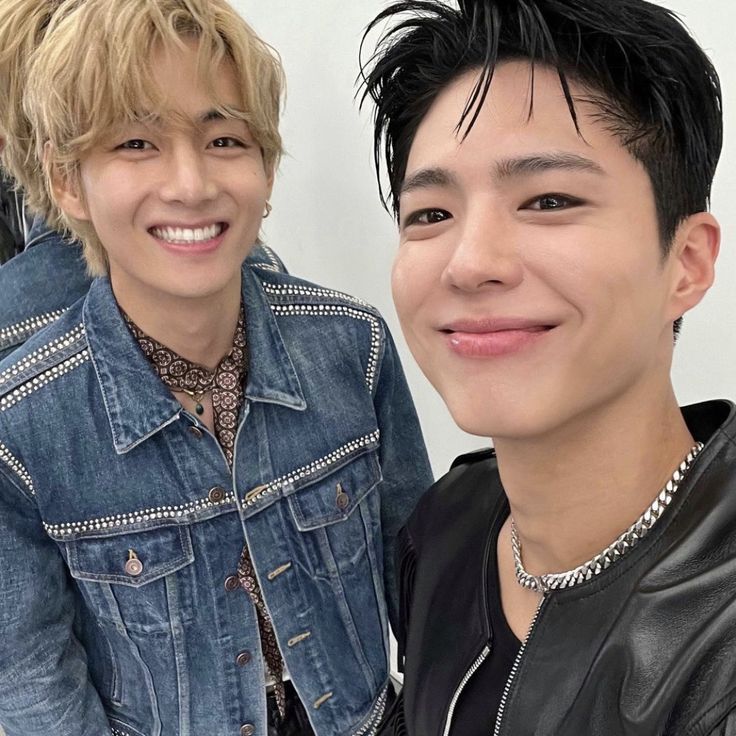 two young men are smiling for the camera while wearing denim jackets and necklaces on their necks