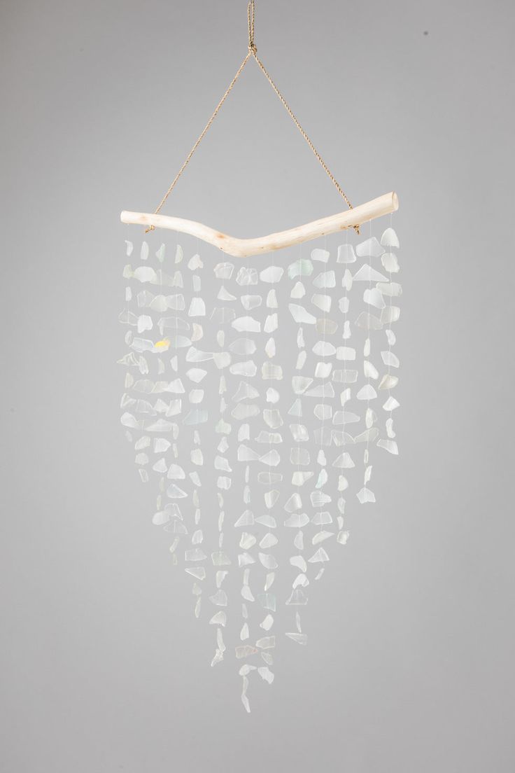 a wind chime hanging from a rope on a gray wall