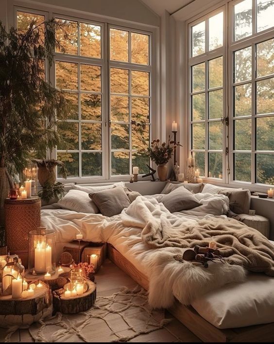 a living room filled with lots of furniture and candles in front of large open windows