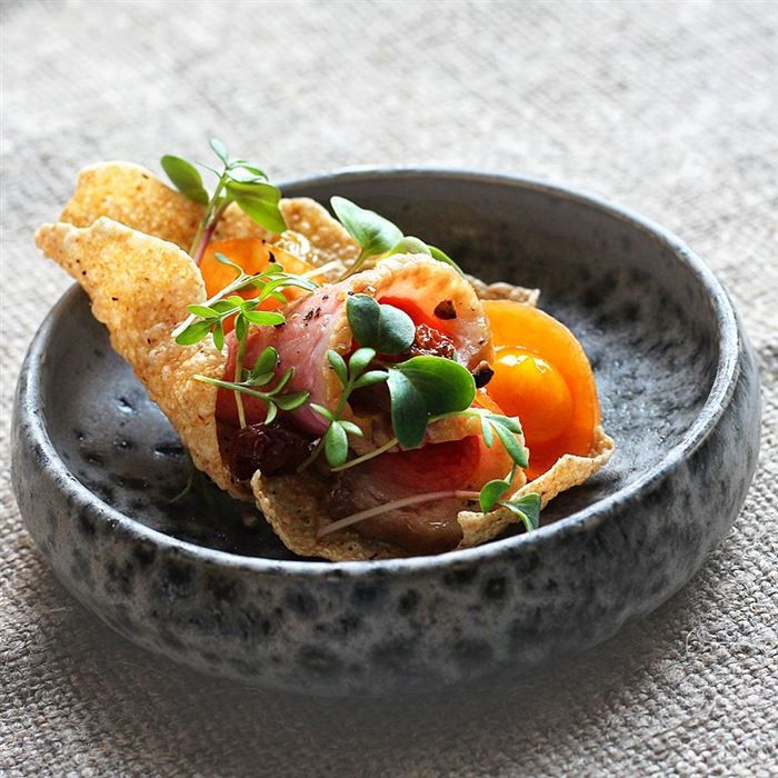 a black bowl filled with food sitting on top of a table next to a cloth