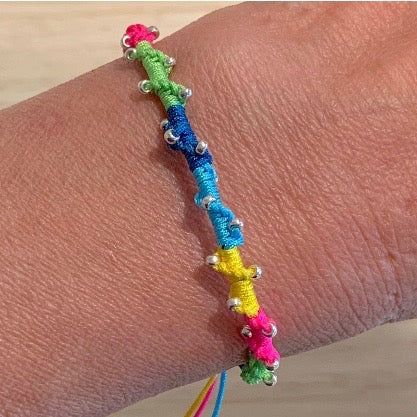 a woman's arm with a bracelet made out of beads and colorful thread on it