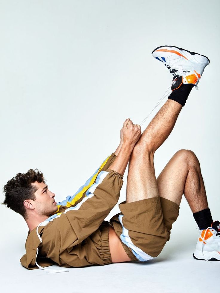 a man laying on the ground with his feet up in the air while wearing shorts and sneakers