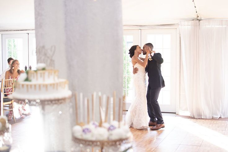 a bride and groom sharing a first dance at their wedding reception in front of the guests