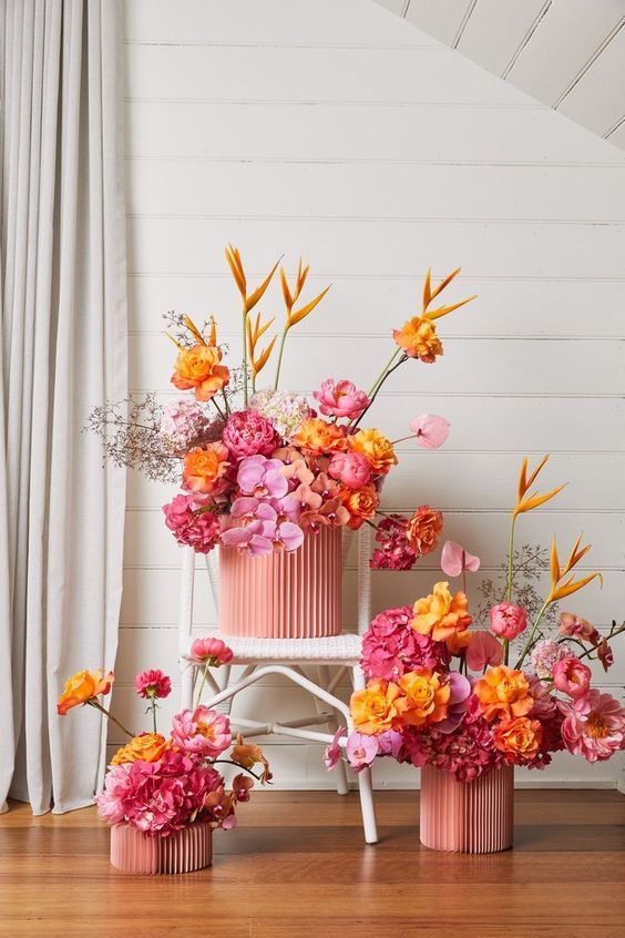 pink and orange flowers in vases on wooden floor