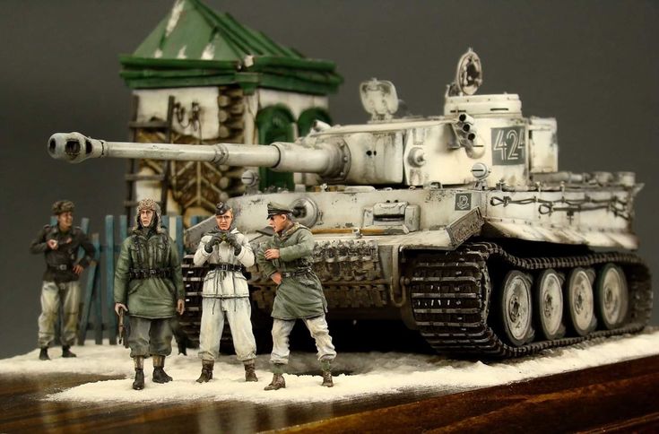 some toy soldiers are standing next to a model tank