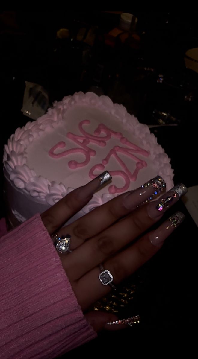 a woman's hand with two rings on her fingers next to a cake