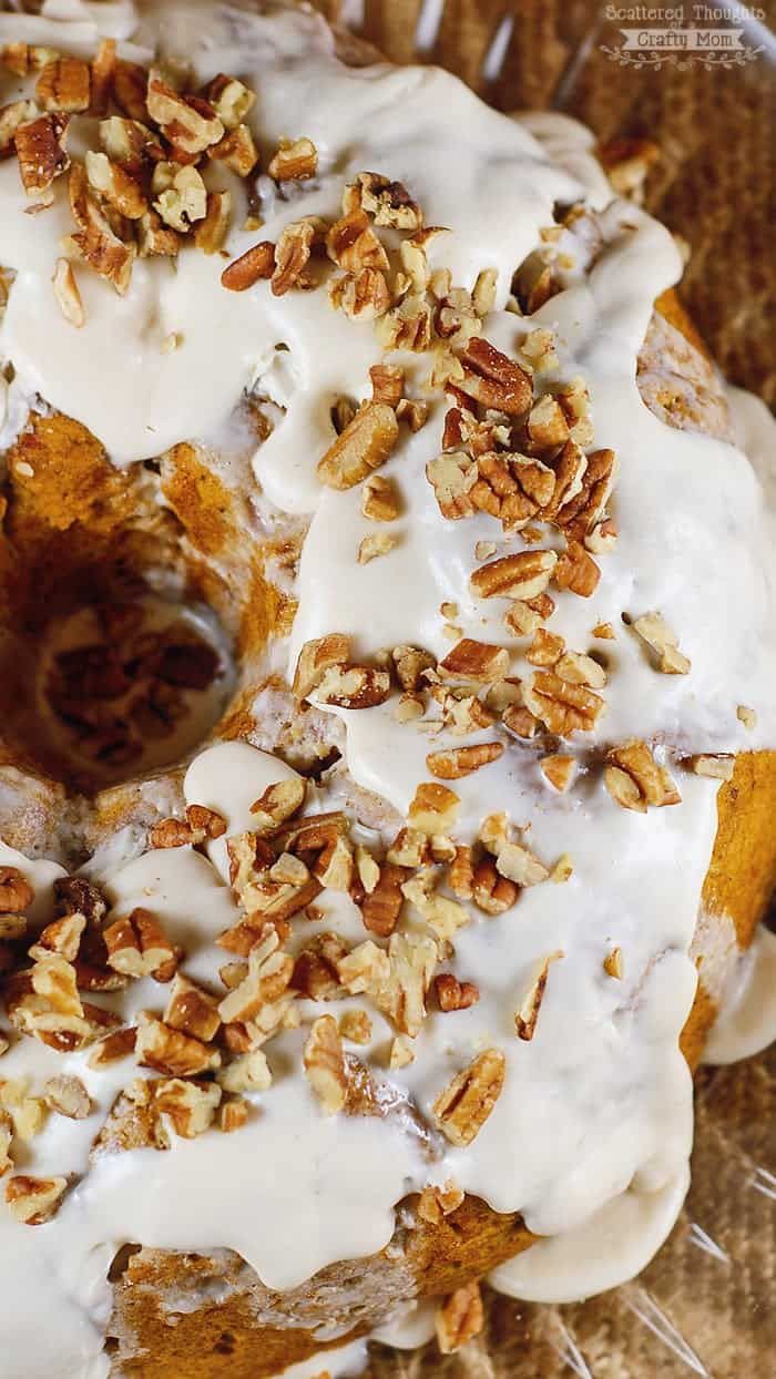 a frosted donut sitting on top of a cooling rack covered in pecans