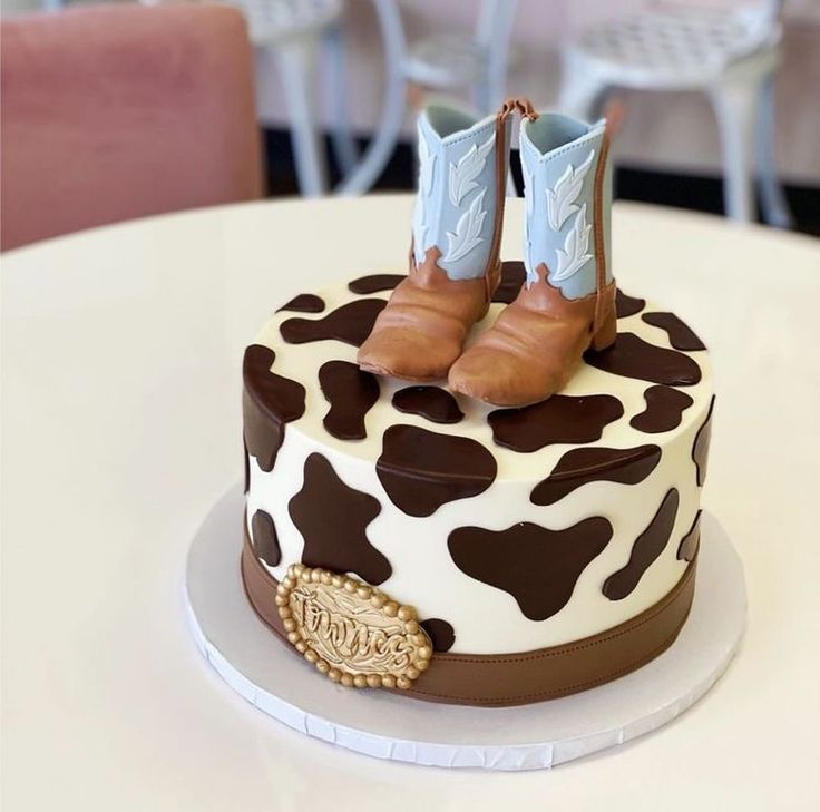 there is a cake decorated with brown and white cow print boots on top of it