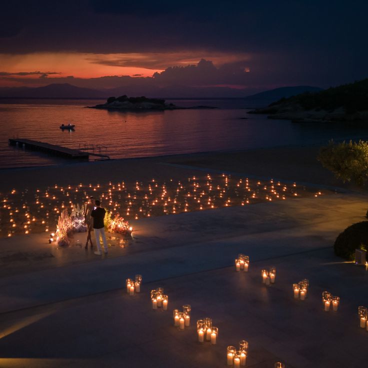 many candles are lit up on the beach at night