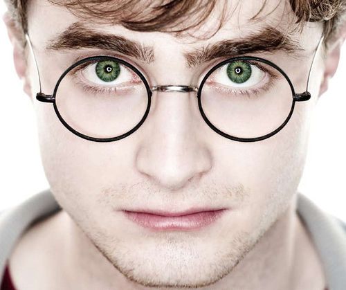 a young man with glasses and green eyes looks at the camera while posing for a portrait