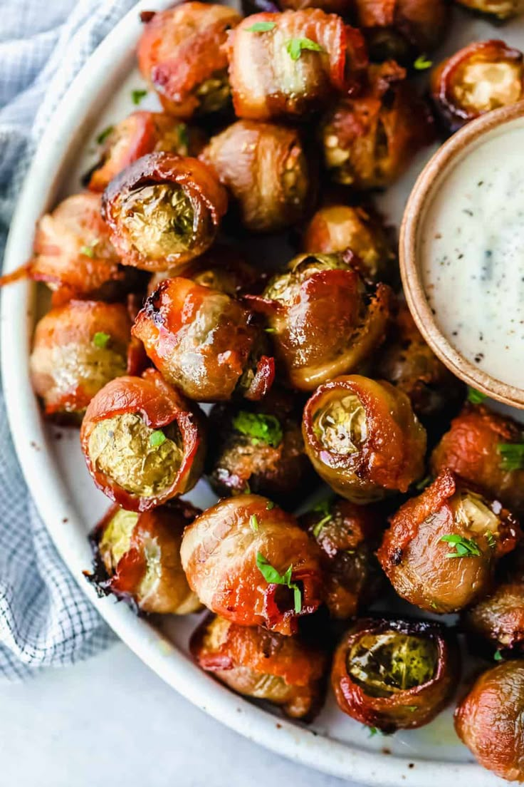 a white plate topped with brussel sprouts next to a small bowl of ranch dressing