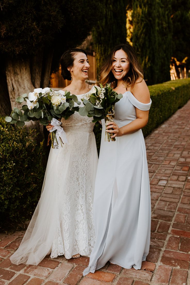 two women standing next to each other holding bouquets