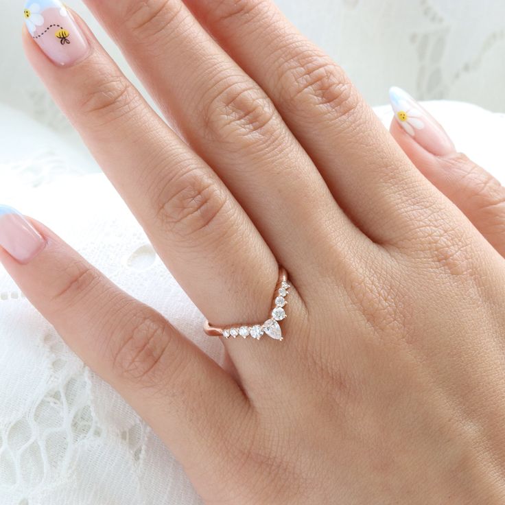 a woman's hand with pink and white nail polish holding a ring on her finger