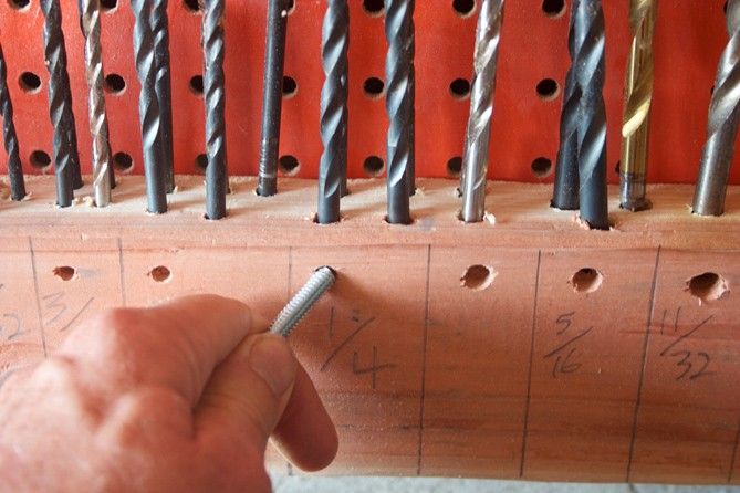 a man is working with drill holes on a piece of wood and screwdrivers