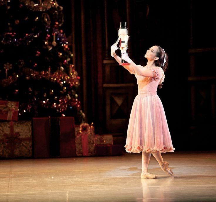 a woman in a pink dress is holding up a glass with a christmas tree in the background