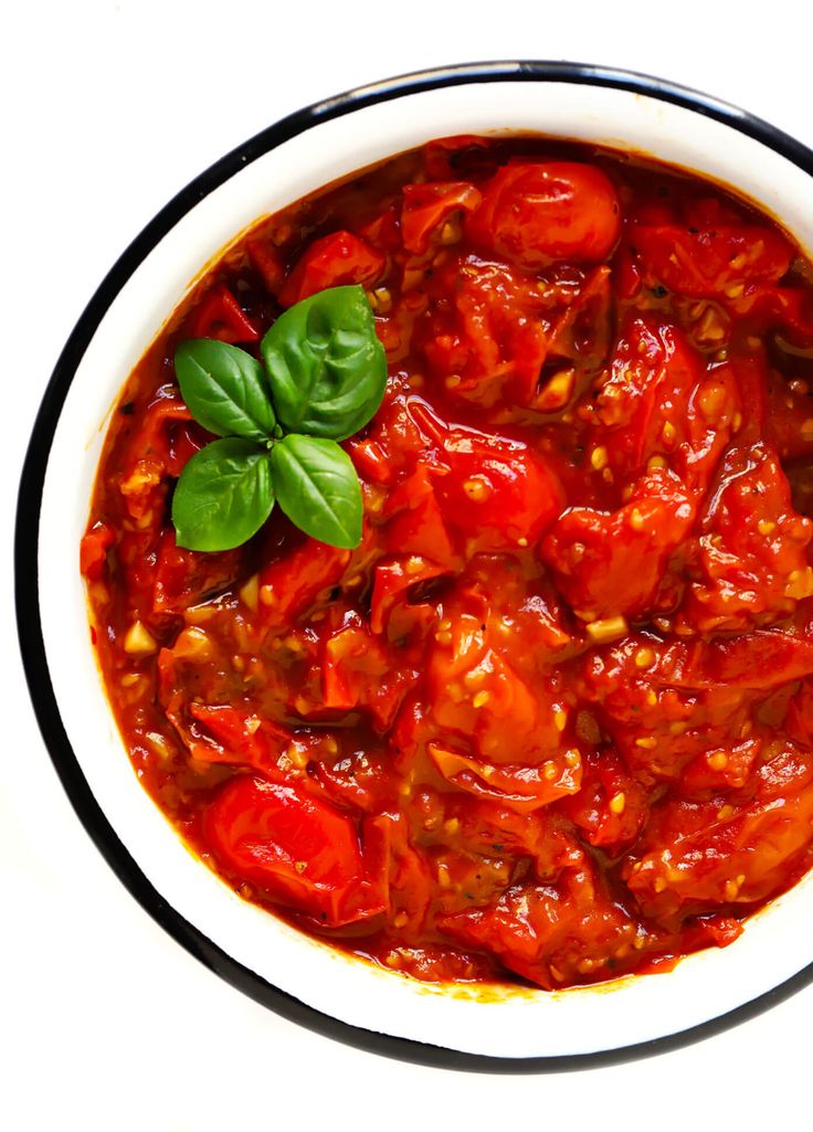 a white bowl filled with tomato sauce and basil