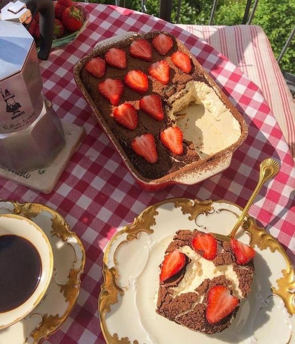 two plates with desserts on them sitting on a table next to cups and saucers