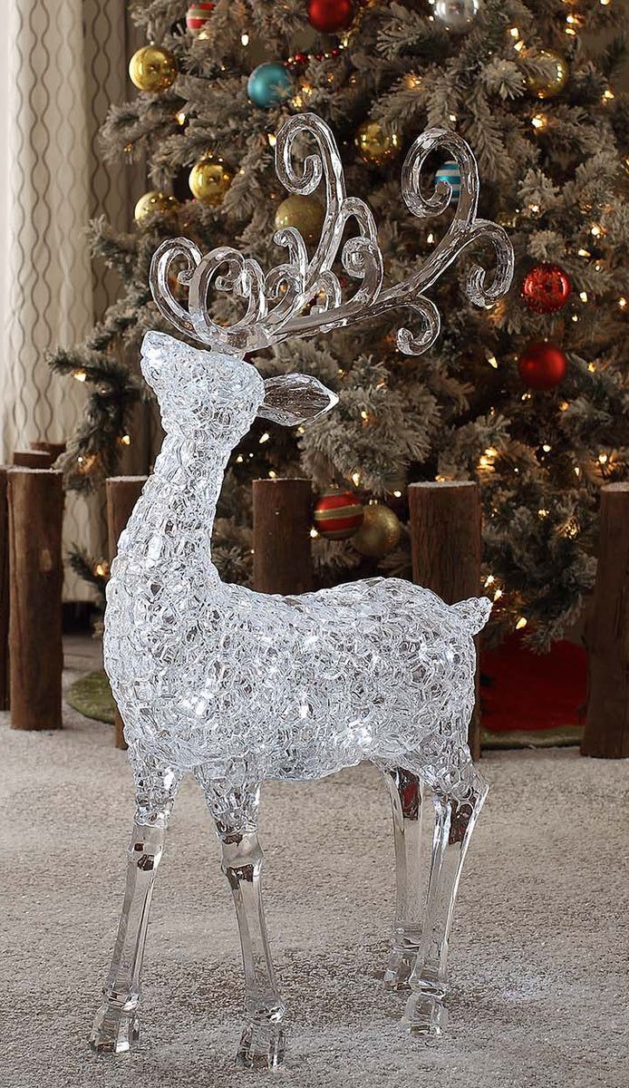 a glass reindeer standing in front of a christmas tree