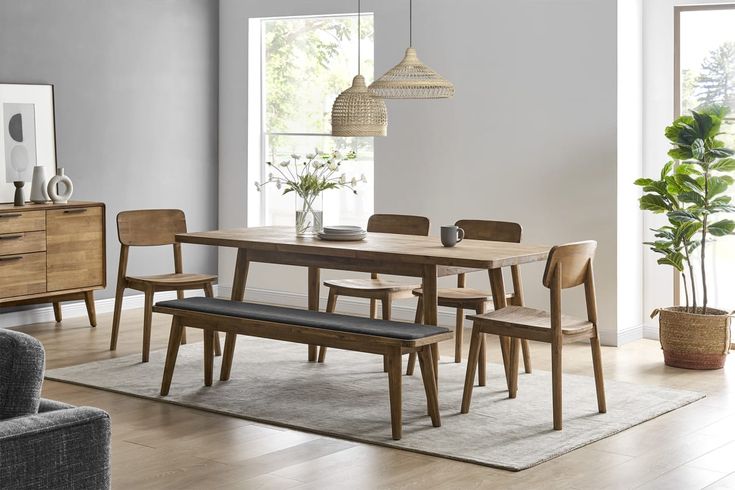 a dining room table and chairs in front of a large window with potted plants