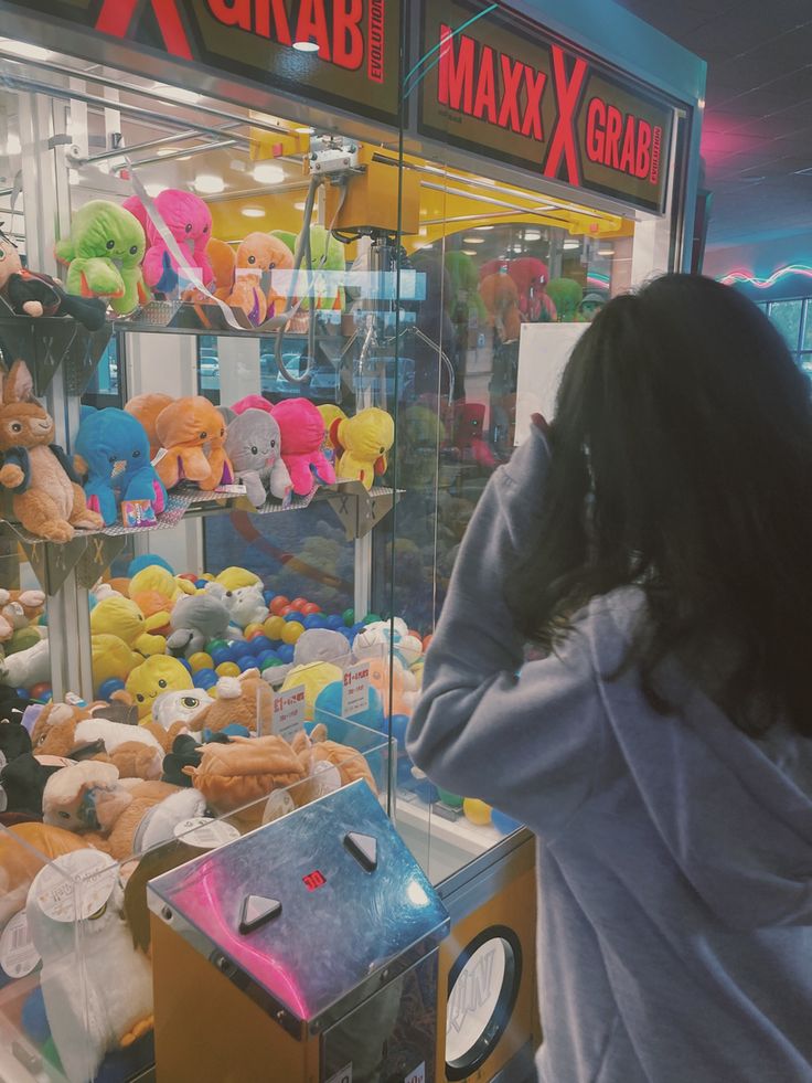 a woman standing in front of a display case filled with lots of stuffed animals and toys