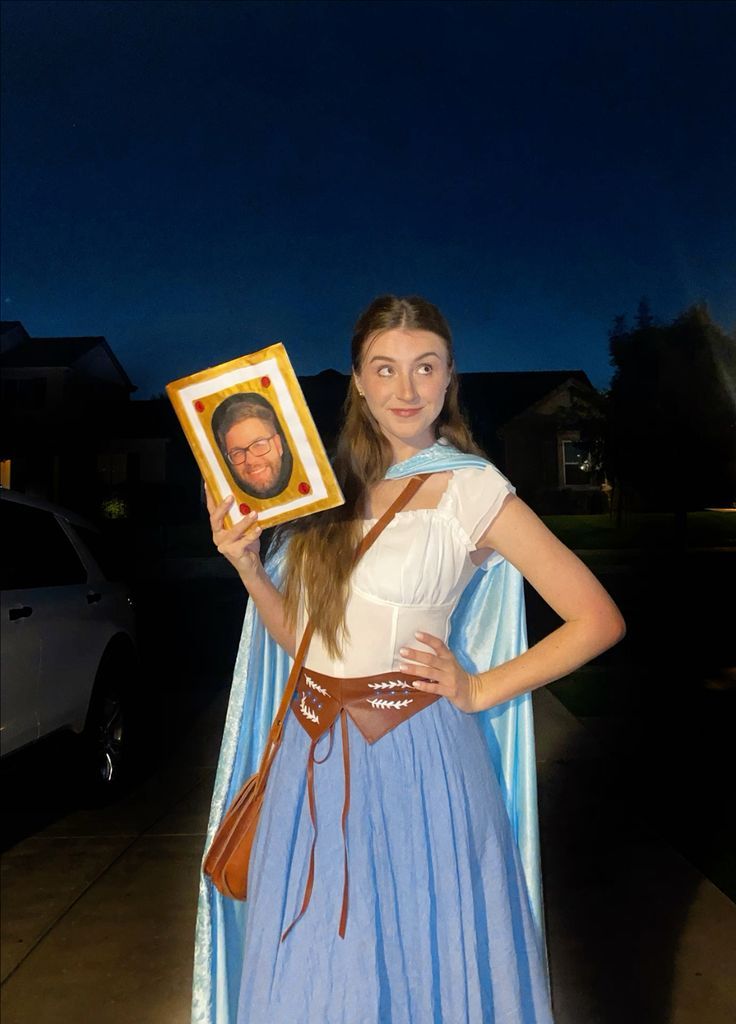 a woman dressed in costume holding up a photo