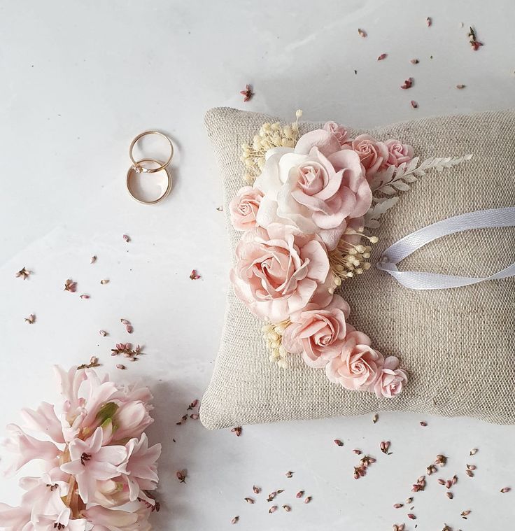 a pillow with flowers on it next to two wedding rings