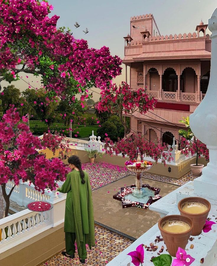 a woman is standing on the balcony looking at flowers and coffee in front of her