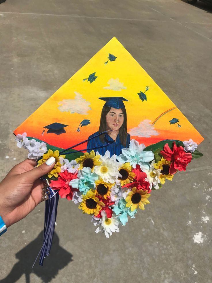 a person holding a graduation cap with flowers in front of it and an image of a graduate