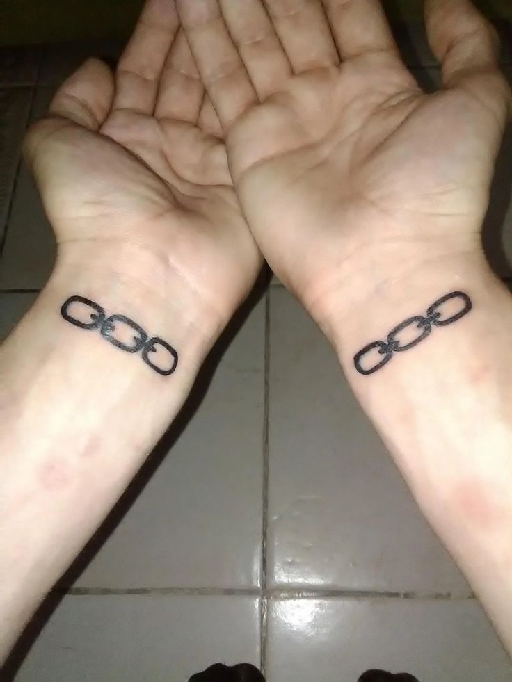 two hands with tattoos on their wrists holding each other's hands in the shape of handcuffs