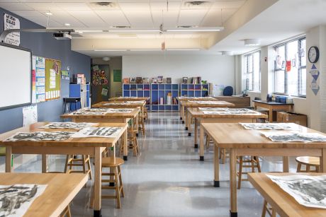 an empty classroom with wooden tables and chairs