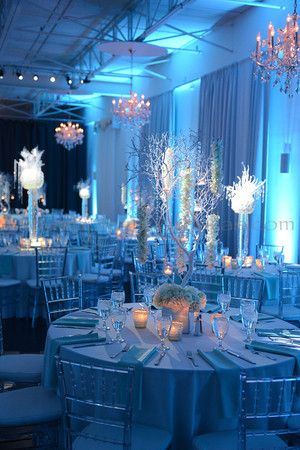 a room filled with lots of tables covered in blue cloths and centerpieces