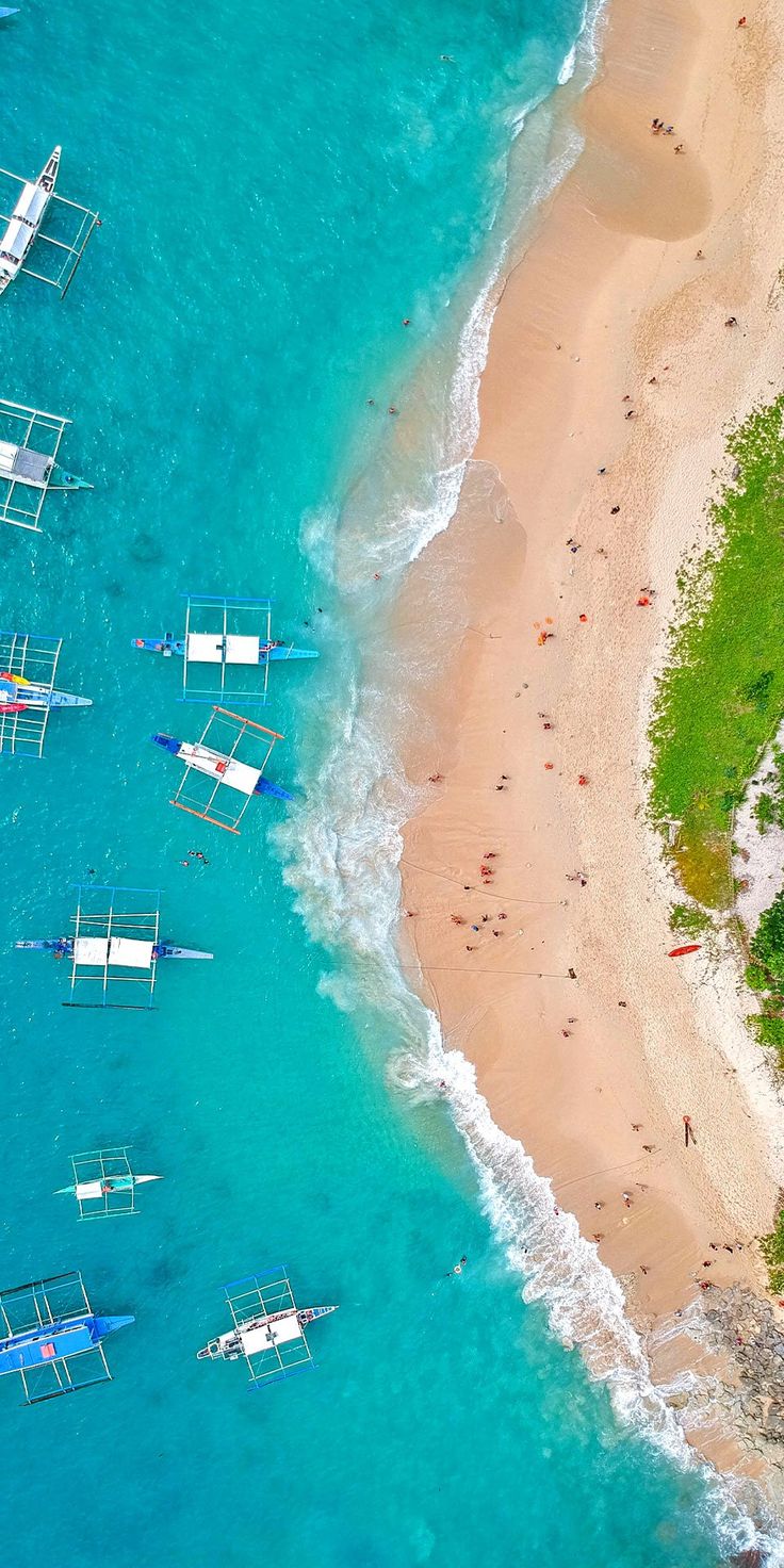 an aerial view of several boats on the water and people swimming in the blue ocean