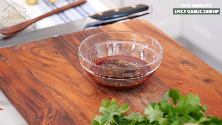 a wooden cutting board topped with a bowl filled with ketchup and garnish