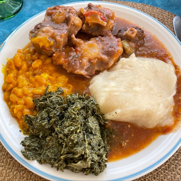 a white plate topped with meat and veggies on top of a blue table cloth