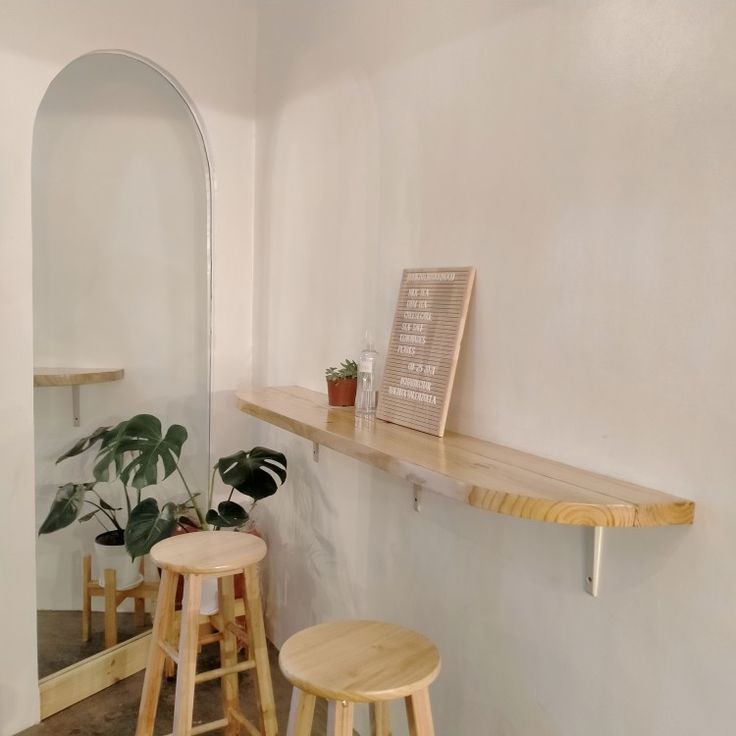 two wooden stools sitting next to each other in front of a wall mounted mirror