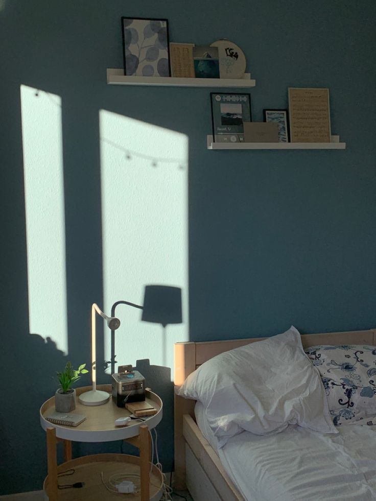 a bedroom with blue walls and white bedding